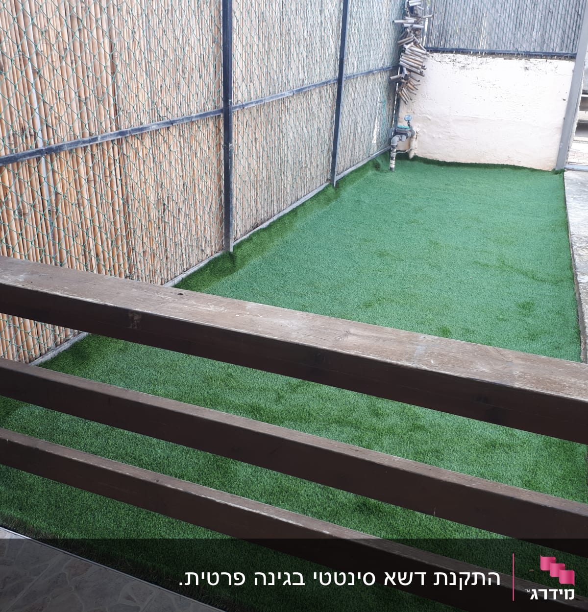 דשא סינתטי על הקרקע ליד גדר מתכת